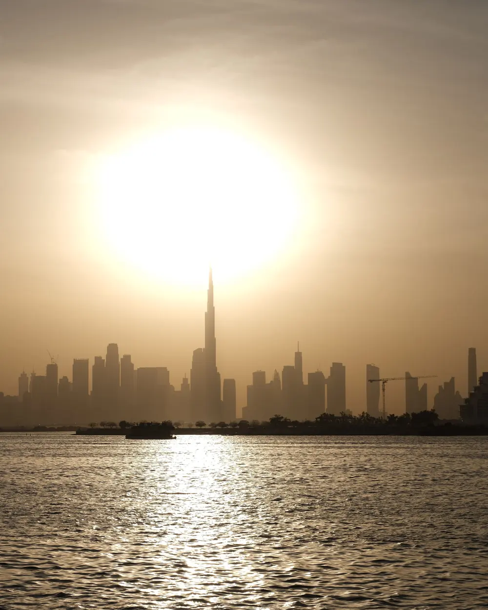 Stunning view of Dubai skyline at sunset, featuring Burj Khalifa towering above cityscape with sun setting behind