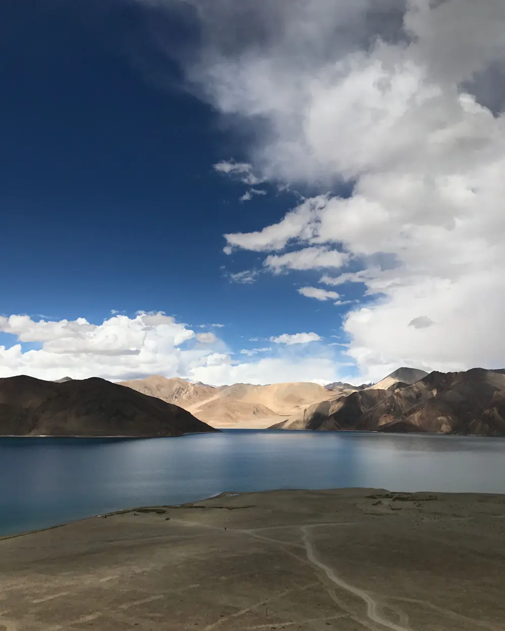 Breathtaking view of Pangong Lake with dramatic clouds and mountain reflections in Ladakh