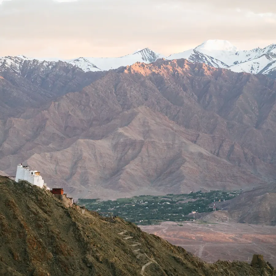 Stunning panoramic view of a monastery perched on a mountain in Ladakh, India with snow-capped peaks