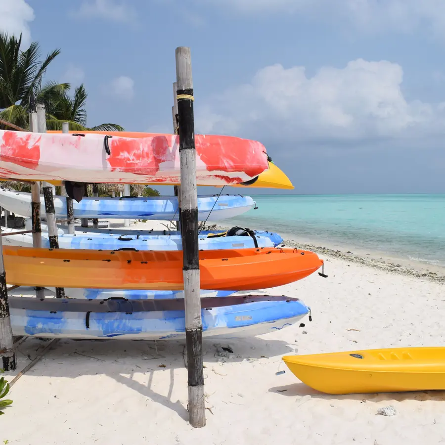 Colorful kayaks stacked on the sandy shores of Minicoy Island, India, with a clear turquoise sea backdrop