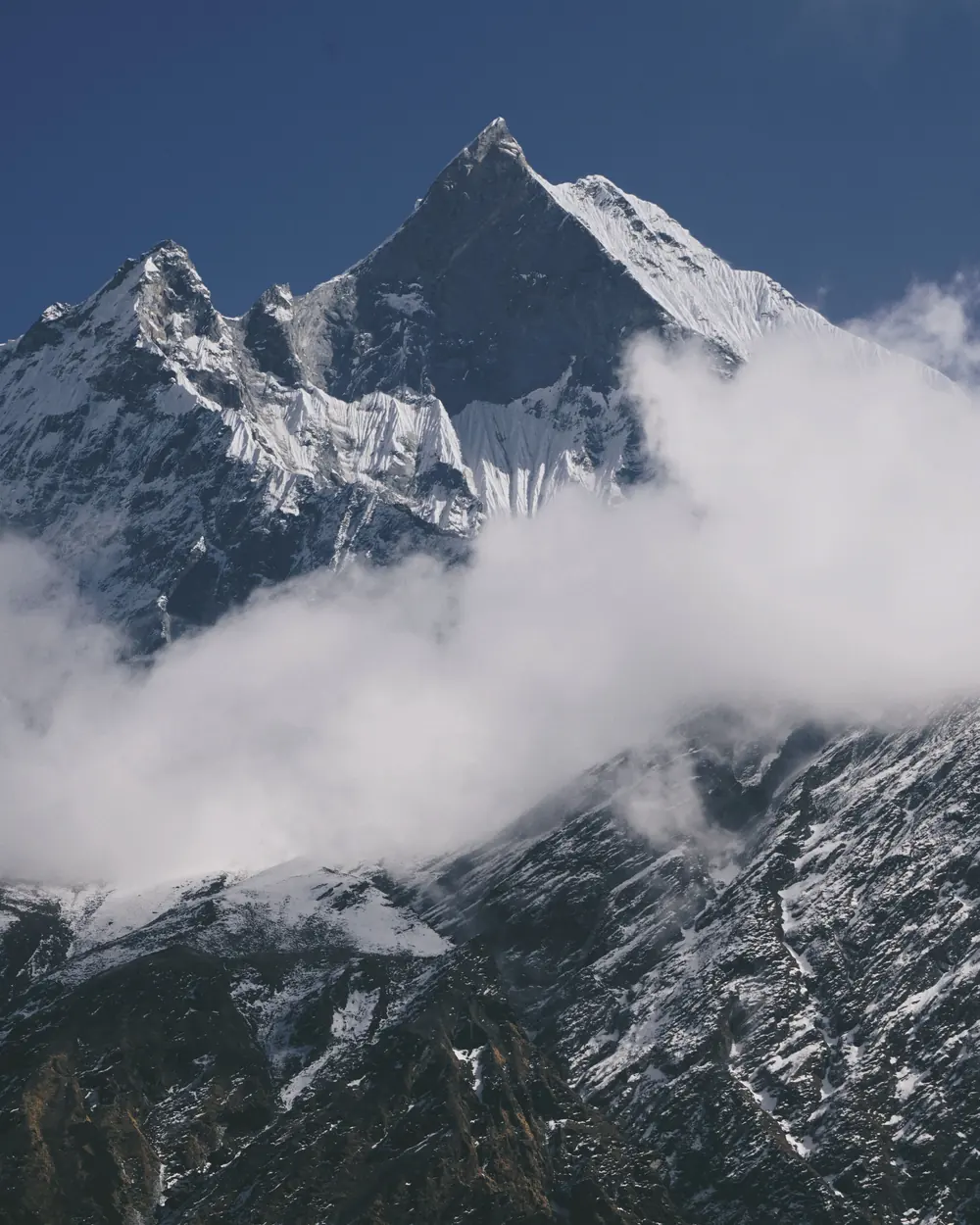 Stunning view of the snow-covered Annapurna mountain peak surrounded by clouds in Nepal's Himalayas