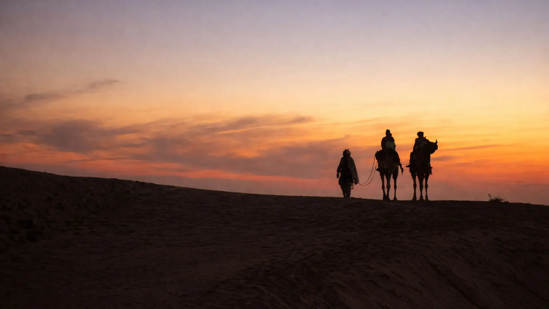 Silhouette of camels and riders during sunset in Sam, Rajasthan's Thar Desert